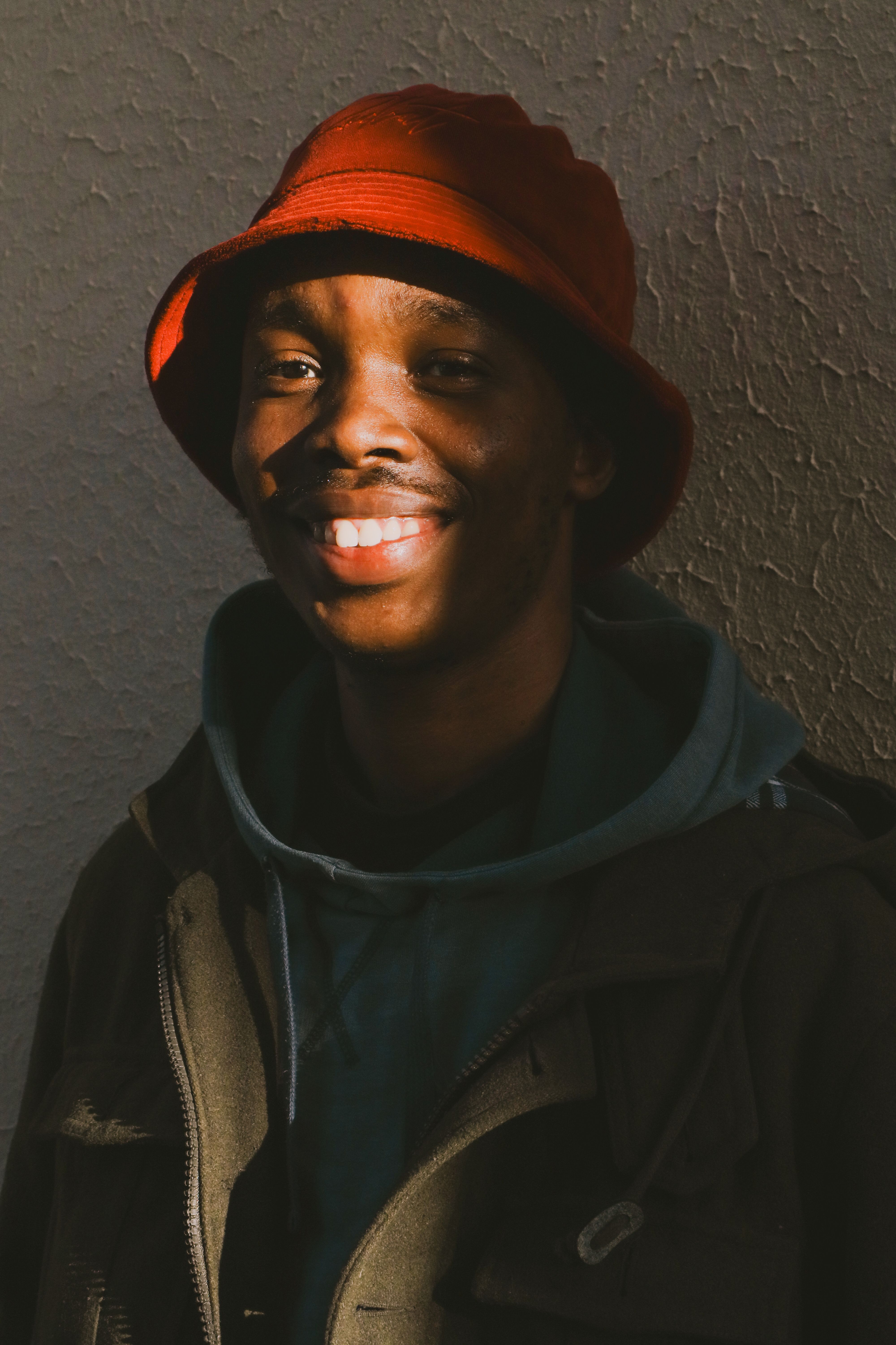 Warm portrait of a man wearing a red bucket hat, captured in gentle sunlight.
