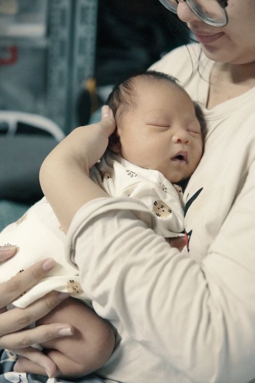 Free A tender moment of a mother gently cradling her newborn baby, conveying warmth and love. Stock Photo