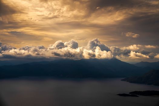 Breathtaking view of dramatic clouds over a mountainous landscape at sunset.