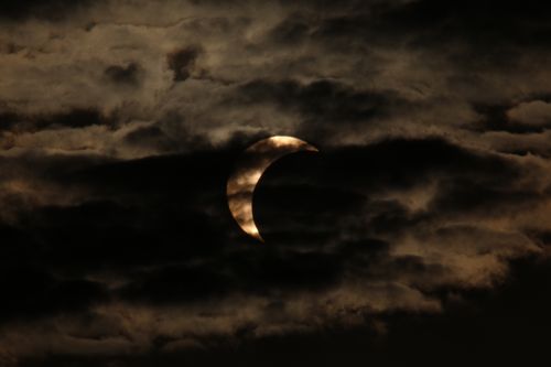 Free A captivating view of a partial solar eclipse partially obscured by dark, dramatic clouds. Stock Photo