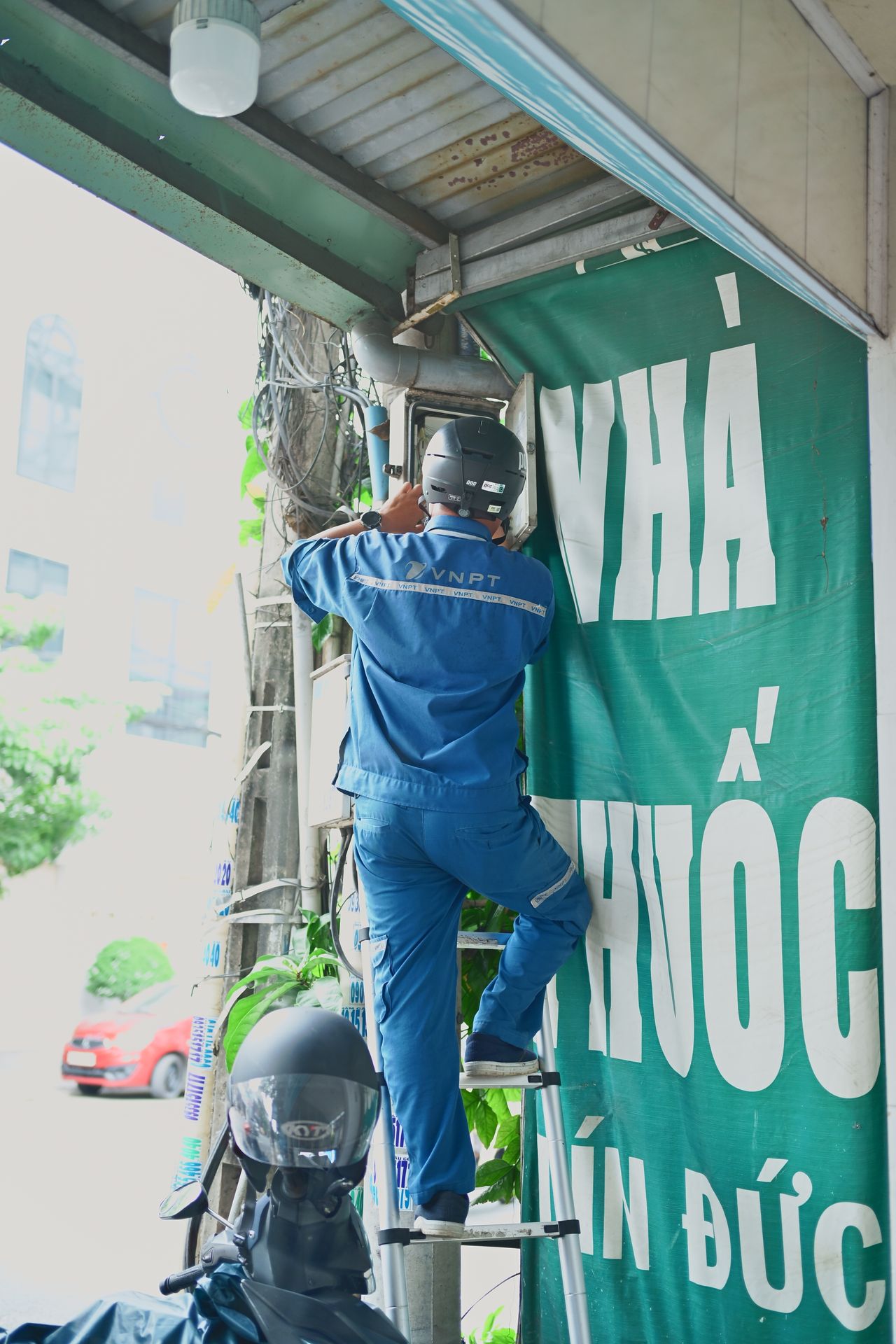 Técnico em escada executando instalação na parte externa de um edifício