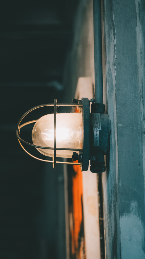 Free Close-up of an industrial wall light with a rustic vibe, highlighting moody lighting. Stock Photo