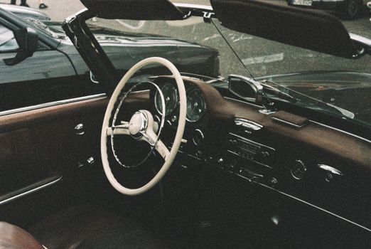 Explore the elegant interior of a vintage convertible car, showcasing a timeless steering wheel and dashboard.