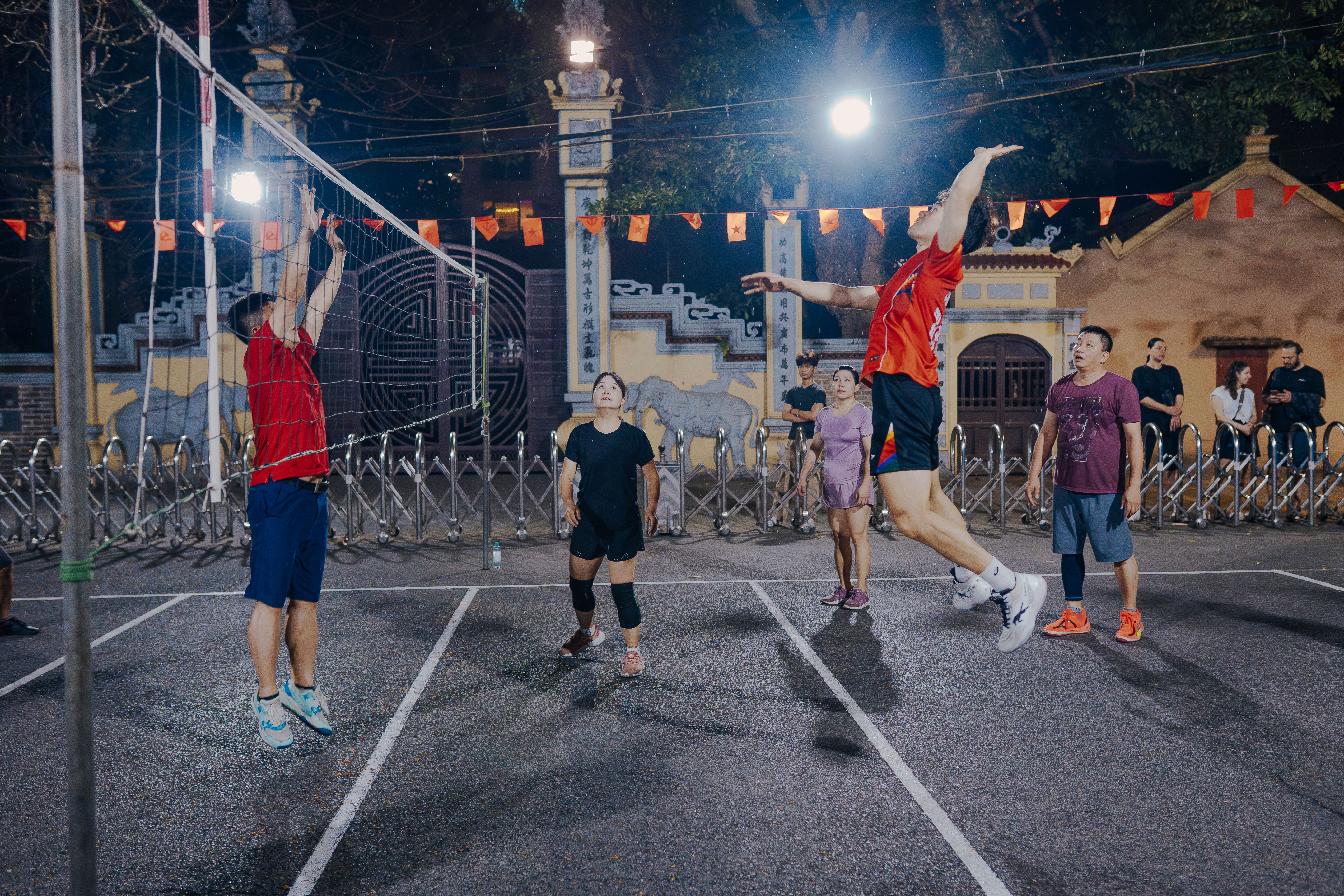 Active Matter: Zaman ve Yerçekimini Bükmeye Hazır Mısınız? - Adults playing a lively night volleyball game in Hanoi, Vietnam, amidst vibrant city lights.