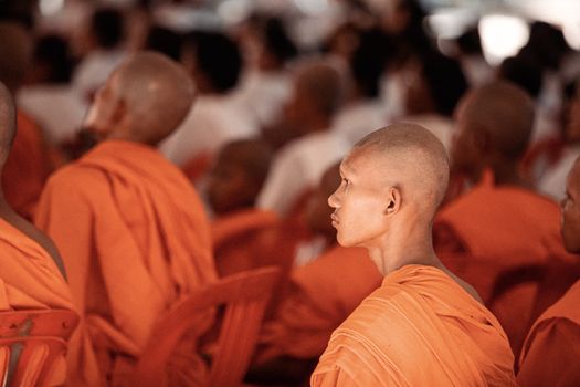 Buddhist monks in orange robes attentively participate in a spiritual gathering in Siem Reap, Cambodia.
