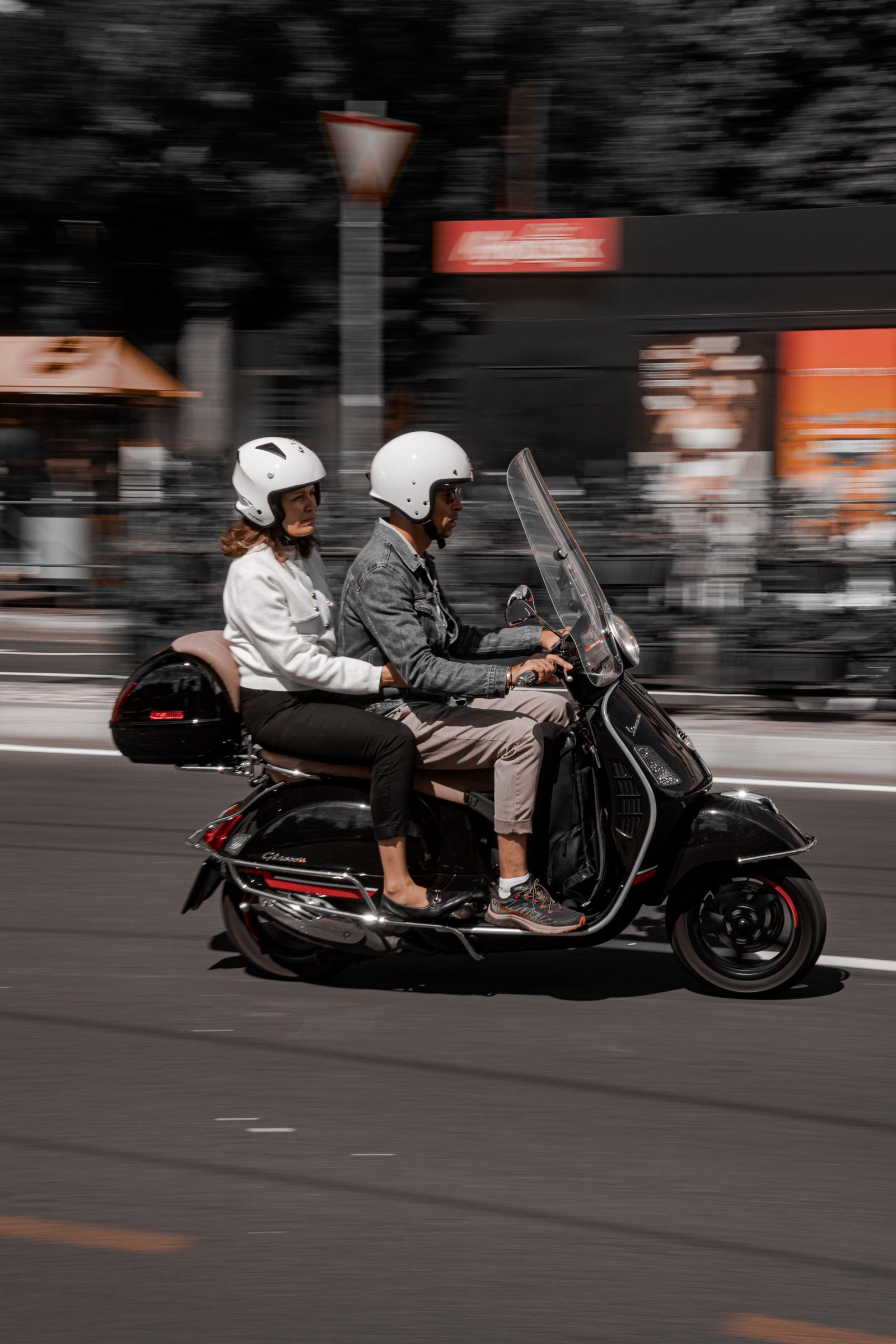 Two people riding a scooter through the city