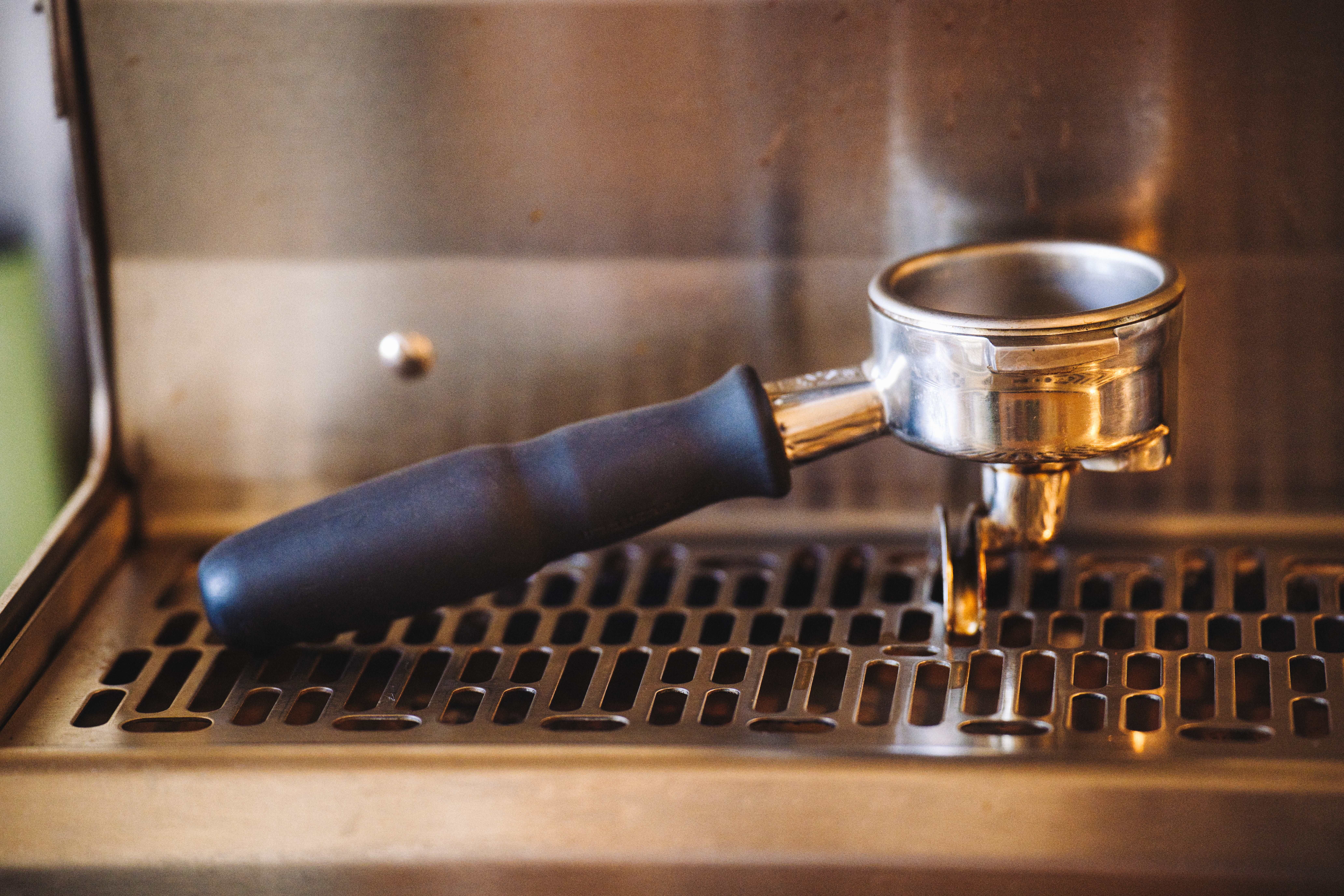 Close-up of a portafilter resting on an espresso machine, ideal for coffee enthusiasts.
