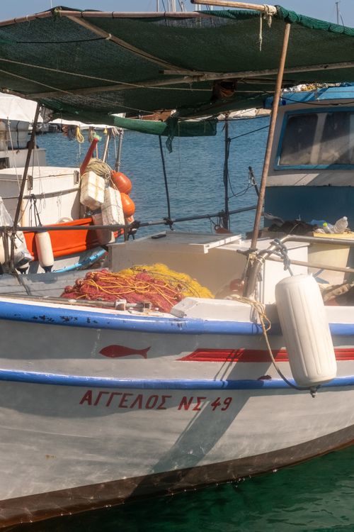 Free A picturesque fishing boat with colorful nets in a Greek harbor, under clear blue skies. Stock Photo