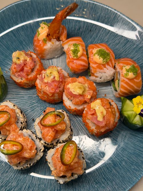 Free A colorful assortment of fresh sushi rolls displayed on a blue plate, featuring salmon, shrimp, and spicy tuna toppings. Stock Photo