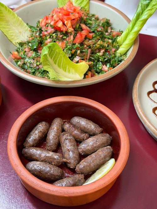 Free Traditional Lebanese mezze with sausages and fresh tabbouleh salad, perfect for Mediterranean cuisine lovers. Stock Photo
