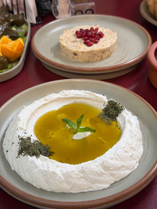 Free Creamy Lebanese labneh drizzled with olive oil, garnished with mint and za'atar, served alongside a rice dish. Stock Photo