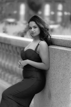 A stylish adult woman posing elegantly against a textured wall in an outdoor setting.
