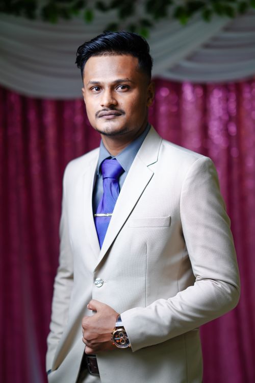 Free A confident man in a light suit with a purple tie poses gracefully indoors. Stock Photo