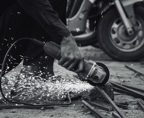 Free Close-up of a worker using an angle grinder on metal, sparks flying. Stock Photo
