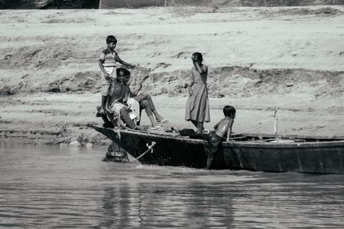 Free A black and white image of people on a boat near a riverbank, emphasizing rural life. Stock Photo