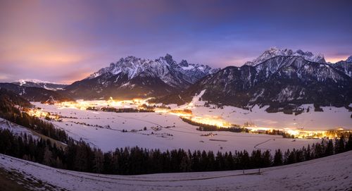 Free Panoramic view of a snowy valley with glowing villages in the Italian Dolomites at twilight. Stock Photo