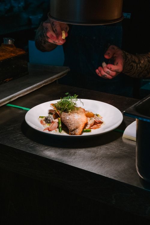 Free A beautifully plated gourmet dish prepared by a chef under warm kitchen lighting. Stock Photo