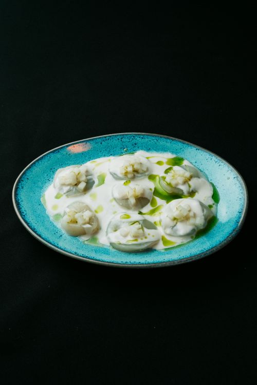 Free A high-end restaurant dish featuring gourmet dumplings in creamy sauce on a blue plate. Stock Photo