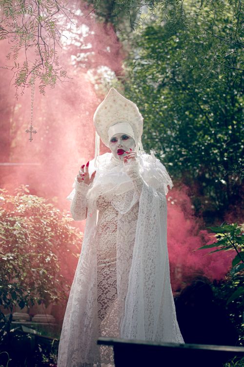 Free Mysterious figure in ornate white lace costume amidst red mist outdoors. Stock Photo