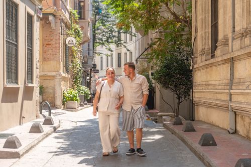 Free Happy couple walking together on a charming European street, enjoying a sunny day. Stock Photo