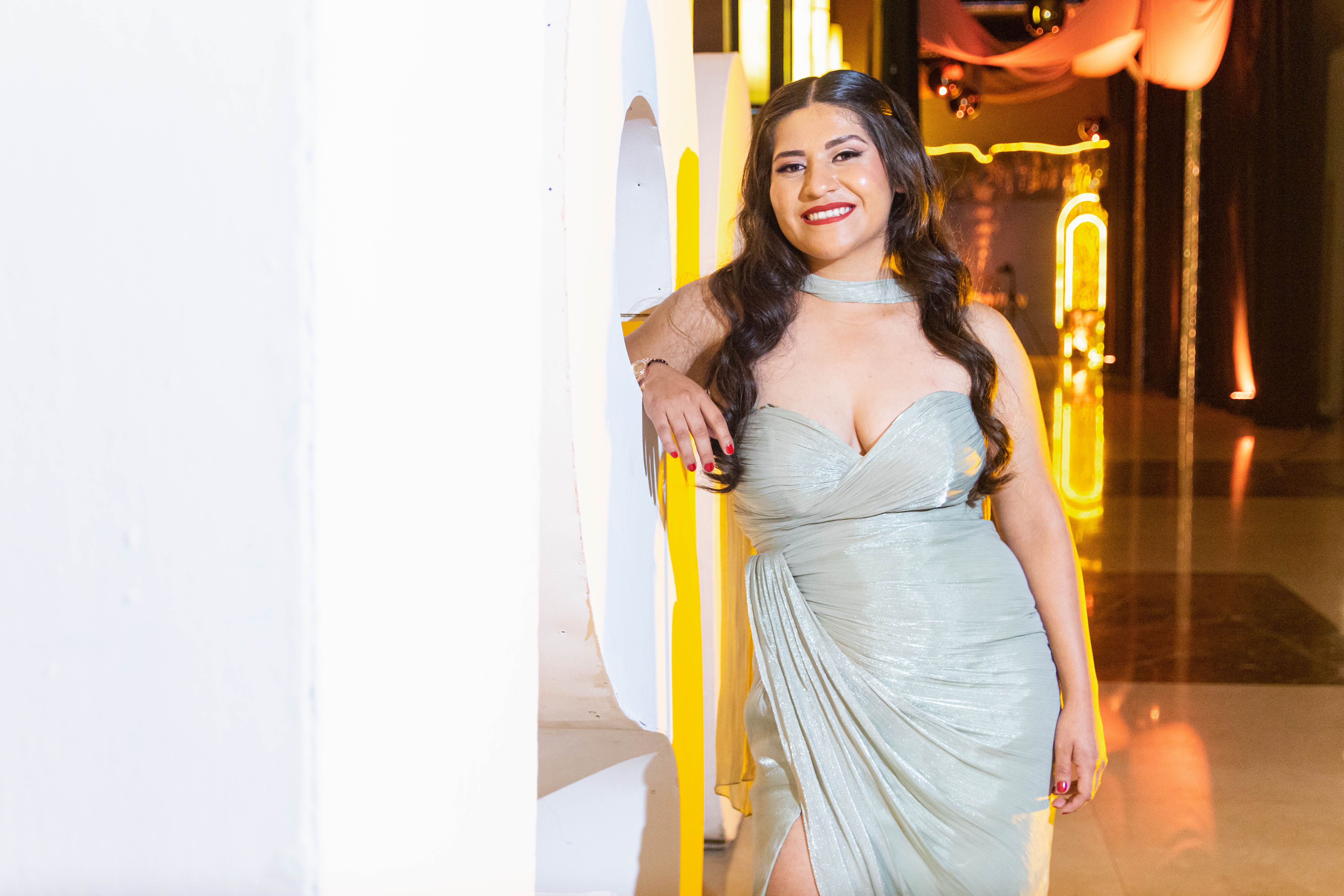 Woman in glamorous evening gown smiling at a classy indoor event.