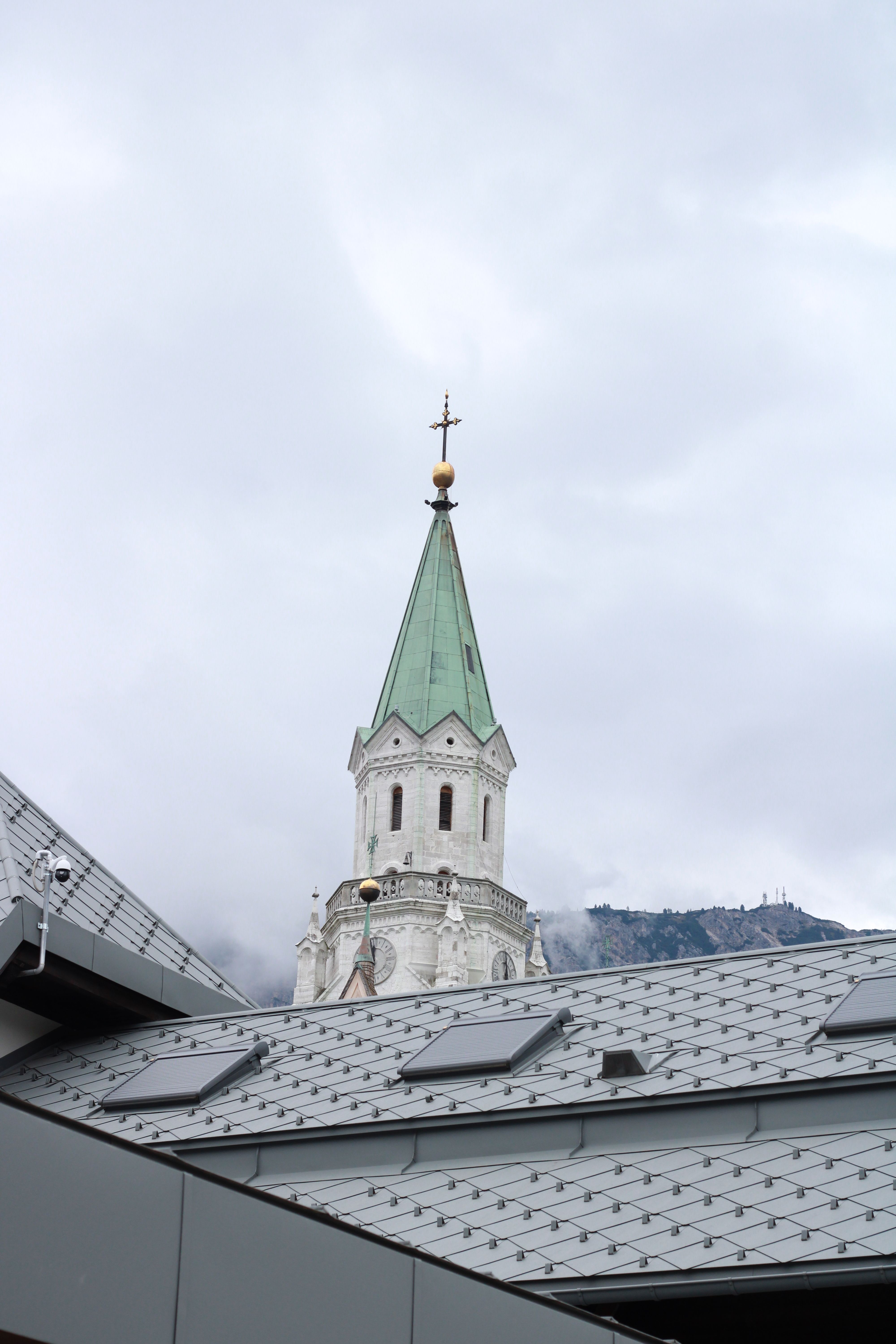 A stunning view of an Italian church spire rising against the backdrop of misty mountains in Veneto, Italy.