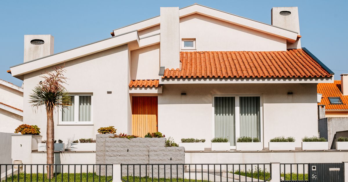 Front view of a modern suburban house with orange roof tiles and a palm tree.