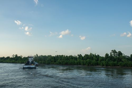 Free Calm river view featuring a boat sailing with clear sky background, lush greenery along the shore. Stock Photo