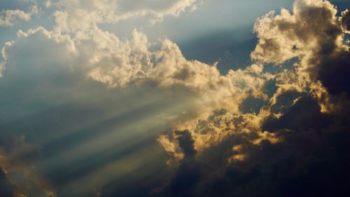 Free Sunlight piercing through dark clouds, creating a dramatic sky scene with rays of light. Stock Photo