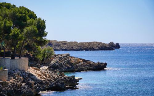 Free Beautiful view of Cala Rajada's rocky coastline and clear blue waters under a bright sky. Stock Photo