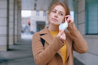 一名妇女在户外脱下外套，摘下口罩，象征着大流行后的自由