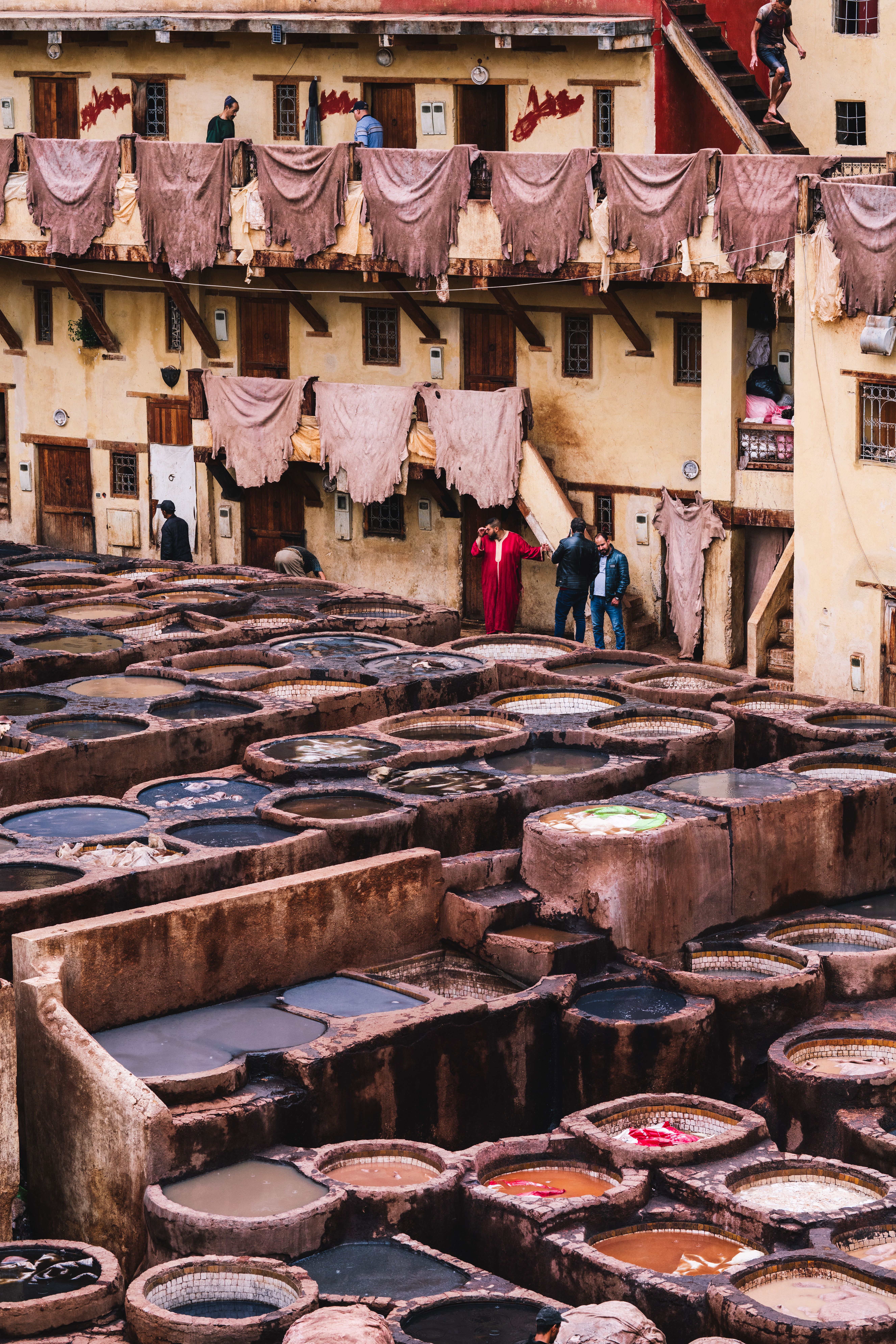 View of historical leather tannery in Fes with people observing the dyeing process.