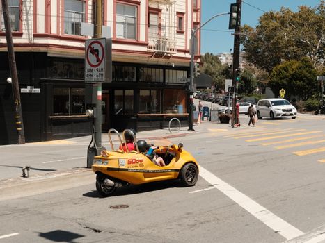 Tourists navigate city streets in a bright yellow GoCar, capturing local sights and urban life.