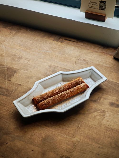 Free A plate of cinnamon churros placed elegantly on a rustic wooden table, perfect for dessert cravings. Stock Photo