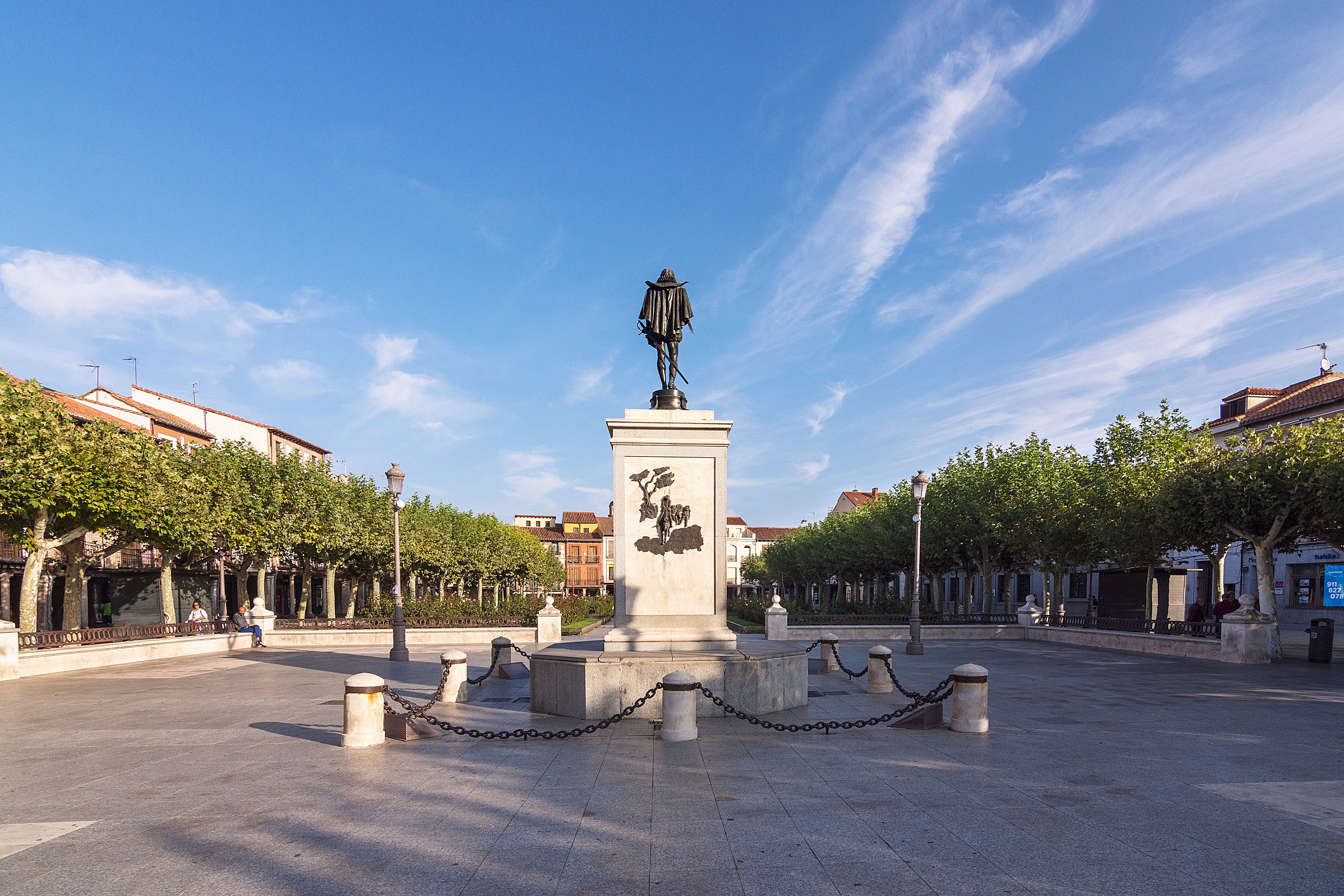 View of the Cervantes Statue in a sunny plaza in Alcalá de Henares, Spain.