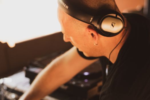 DJ wearing headphones and mixing music at a live indoor event, creating vibrant atmosphere.
