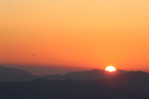 Free Vibrant sunset with silhouette of mountains and an airplane in the sky. Stock Photo