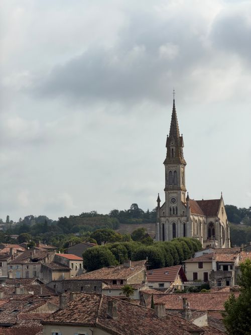 Free View of a historic church rising above the traditional rooftops of a French village. Stock Photo
