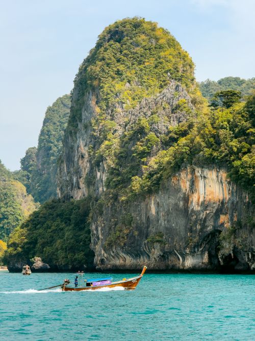 Free Traditional longtail boat against Krabi's stunning karst landscape and turquoise waters. Stock Photo