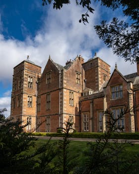 A beautiful historic brick mansion set against a vibrant blue sky and lush greenery.
