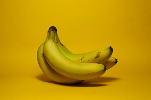 Free A vibrant image of a fresh bunch of bananas against a bold yellow background. Stock Photo