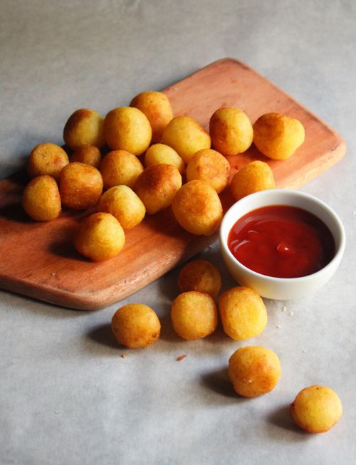 Free Delicious golden potato bites served with tangy red sauce on a rustic wooden board. Stock Photo