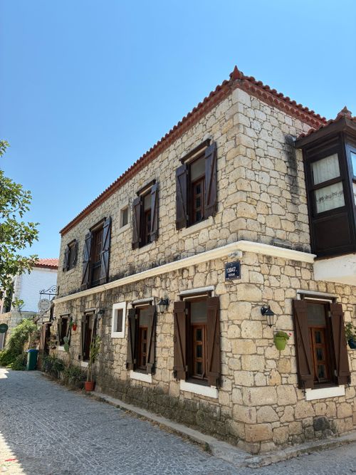 Free Beautiful stone house on a cobblestone street in Alaçatı, Turkey, under a bright summer sky. Stock Photo