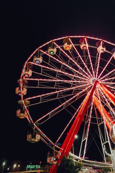 A dazzling Ferris wheel illuminated with neon lights against a night sky at a lively carnival.
