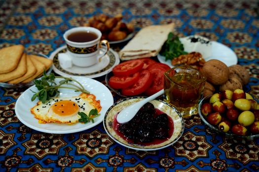 A rich Persian breakfast featuring tea, eggs, tomatoes, and traditional bread.