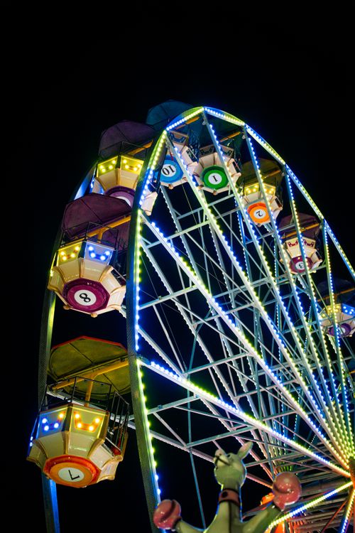 Free Colorful ferris wheel illuminated with neon lights at a night festival. A vibrant scene capturing fairground excitement. Stock Photo