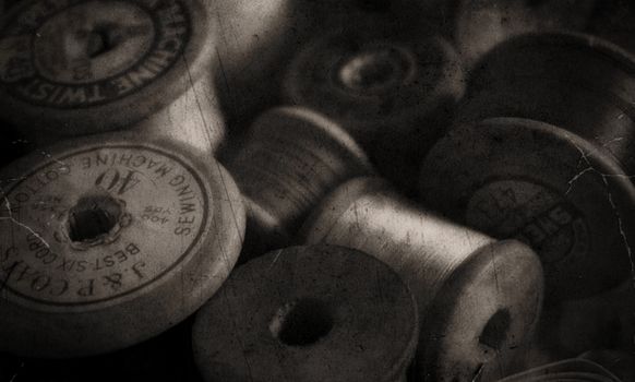 Artistic close-up of vintage sewing thread spools in grayscale, capturing a nostalgic still life scene.