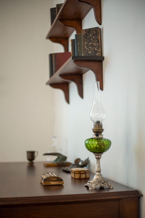 Free Elegant vintage setting with an oil lamp, books, and antiques on a wooden desk. Stock Photo