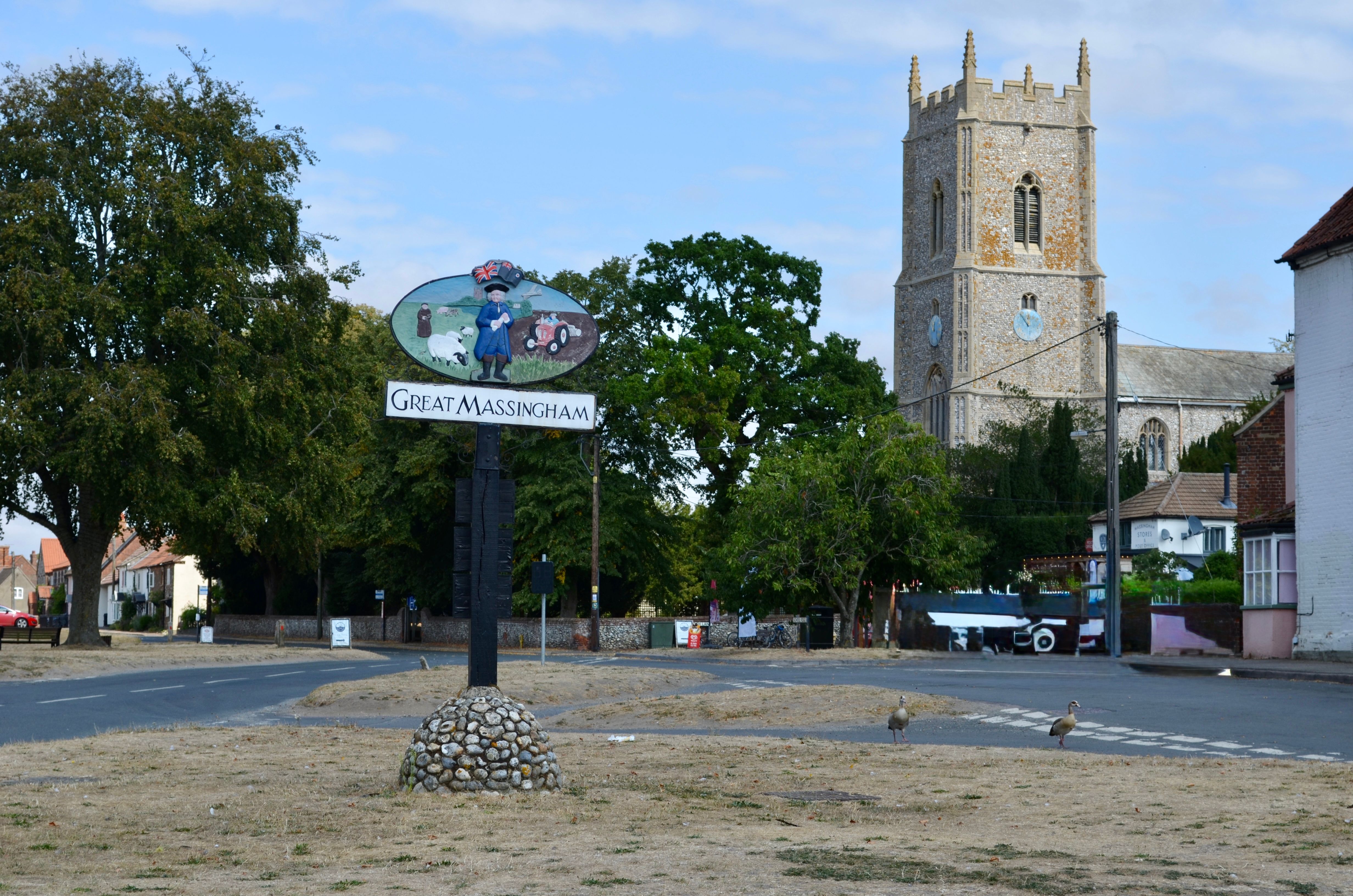 Scenic view of Great Massingham village with St Mary's Church and signpost.
