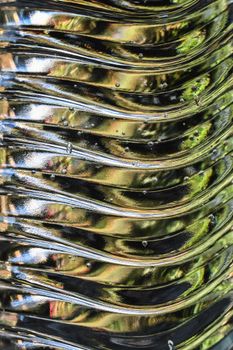 Close-up of a wavy metal surface with light reflections creating an abstract pattern.
